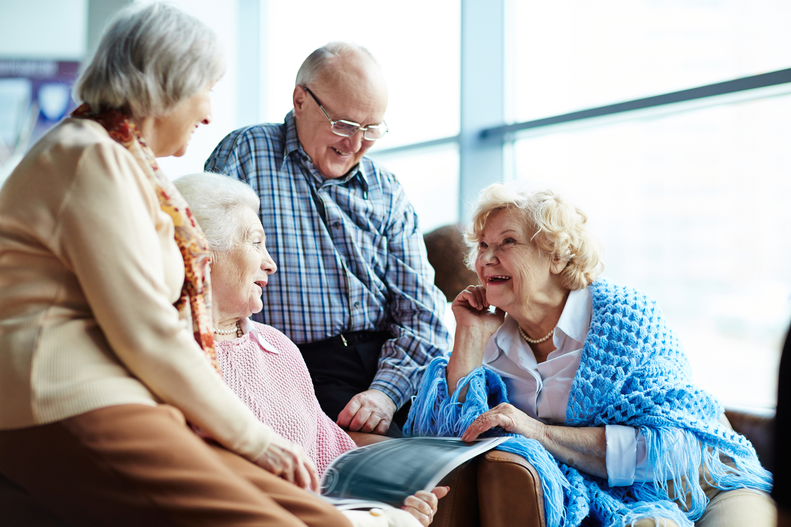 group of elderly people happily talking in assisted living facility